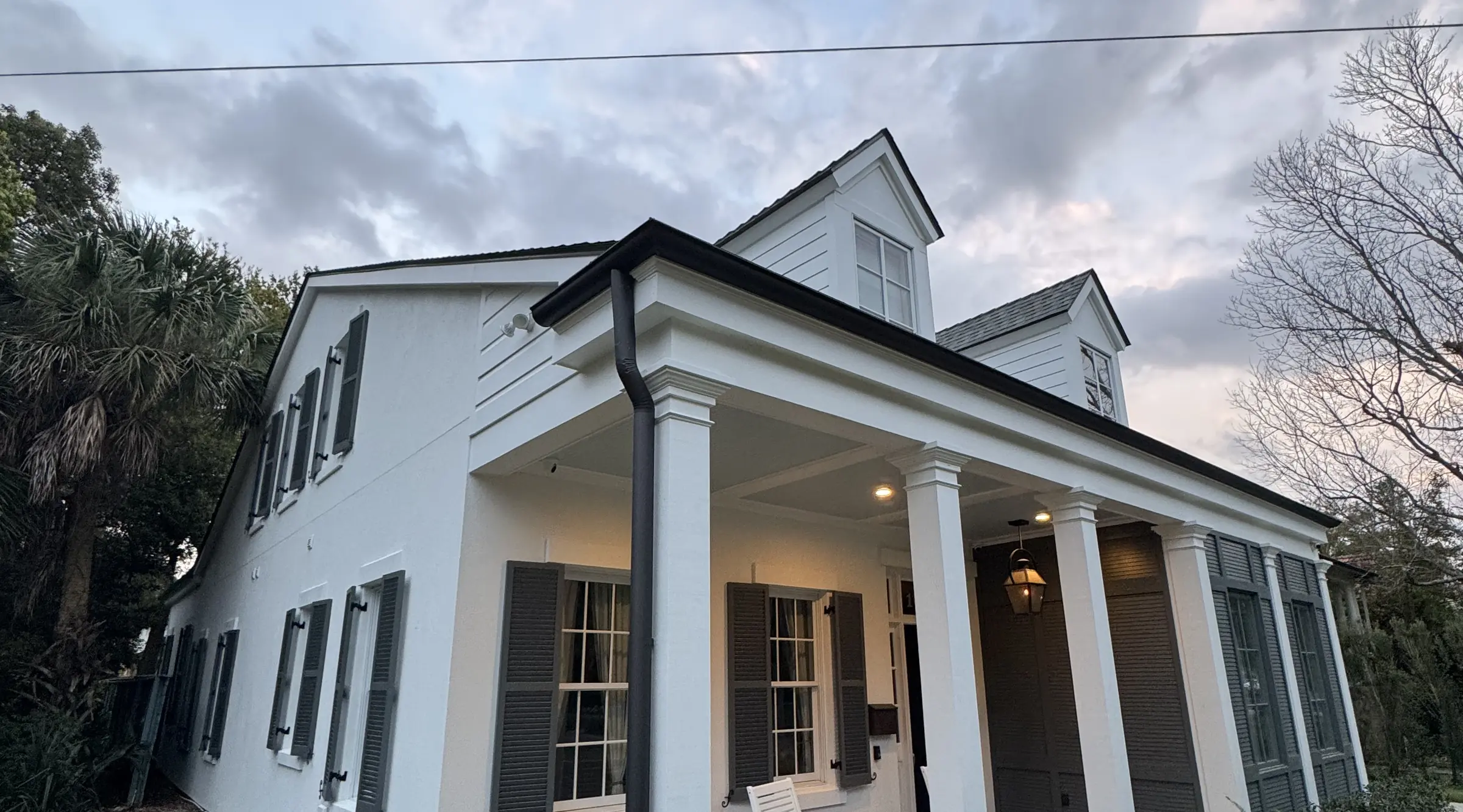 White exterior paint with dark shutters on a two-story home with a columned front porch